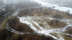 Mglisty widok z lotu ptaka na okolicę ulicy Na Grobli i Międzyrzeckiej we Wrocławiu z kładką nad rzeką i śladami opon na śniegu.