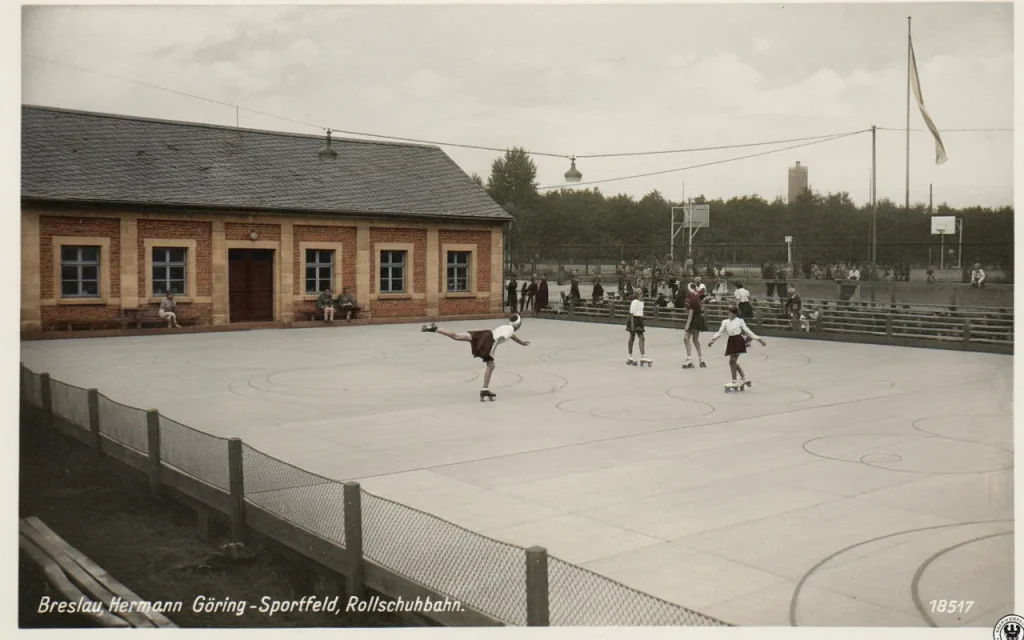 Koloryzowane zdjęcie archiwalne przedstawiające wrotkowisko na dawnym polu sportowym we Wrocławiu w 1942 roku z łyżwiarzami figurowymi na wrotkach.