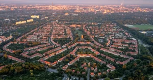Widok z lotu ptaka na zabytkowe osiedle Sępolno we Wrocławiu, przedstawiający unikalny układ urbanistyczny i architekturę z czerwonymi dachami pośród zieleni.